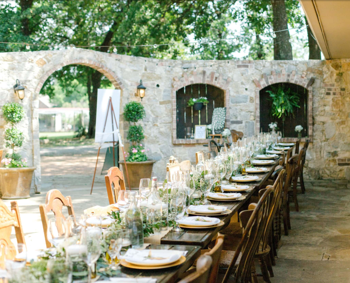 Mesas de celebración bajo los arcos de piedra y los árboles de Fortunata Winery